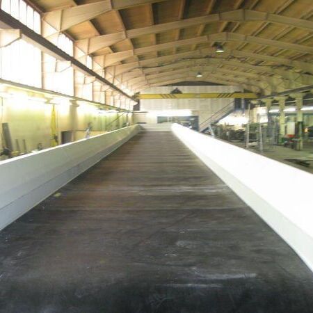 Belt conveyor as a flat runner with tight roller pitch for the transport of complete stone packages